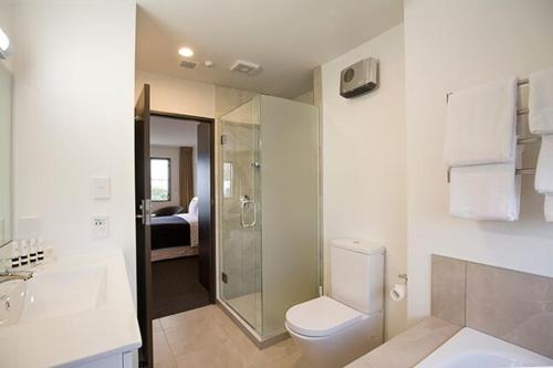 a white bathroom with a toilet and a shower at Pavilions Hotel in Christchurch