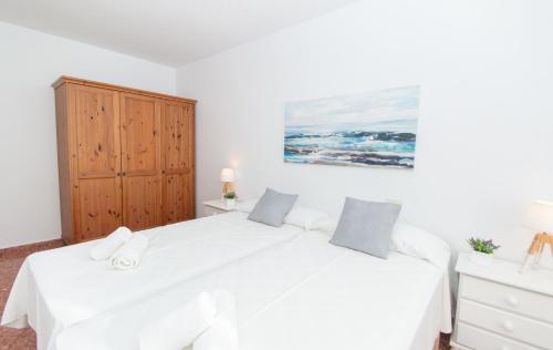 a bedroom with two white beds and a wooden cabinet at Villa Can Canaleta by Sonne Villas in Cala Galdana