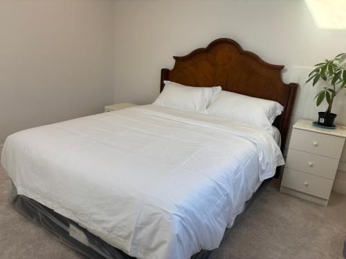 a bedroom with a white bed with a wooden headboard at Comfortable Private Room in a Shared Home in Richmond