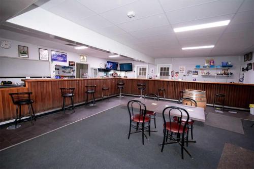 a large room with a bar with chairs and a counter at Commercial Hotel in Birchip