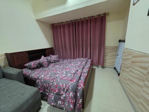 a bedroom with a bed with a purple comforter at Ajman Downtown Central AISOOGA in Ajman 