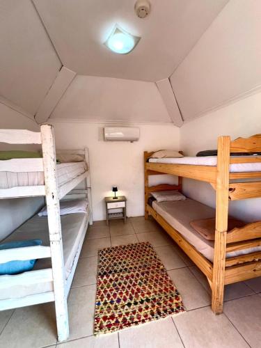 a room with three bunk beds and a rug at Del Barcito Hostel and Suites in Punta del Este