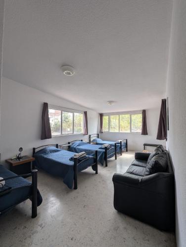 a room with four beds and couches and windows at Casa Amari - Para 17 Personas - Grupos y Eventos in Morelia