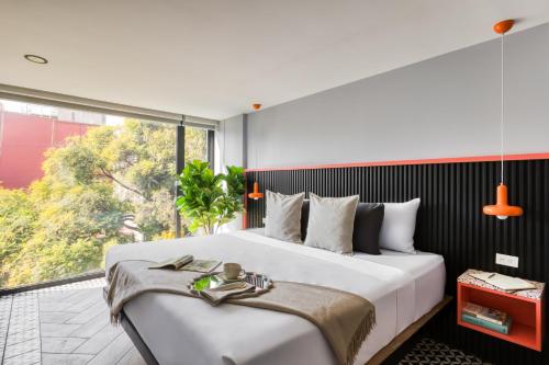 a bedroom with a large bed and a large window at ULIV Condesa in Mexico City