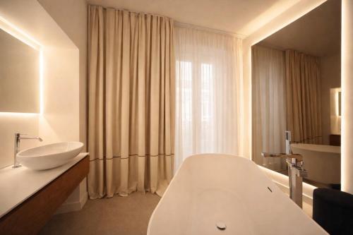a bathroom with a white tub and a sink at Mamalu - Corso Umberto 35 - Studios and Suites in Naples