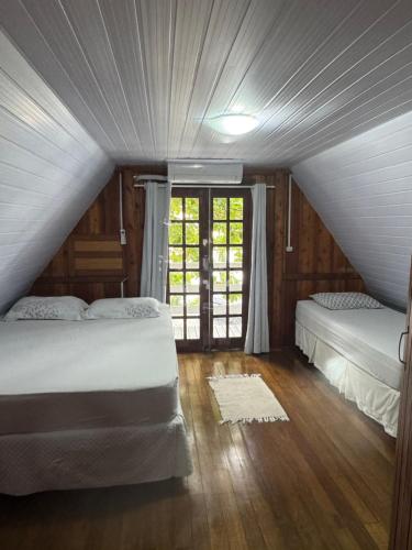 a attic bedroom with two beds and a window at Cabanas da Vó Nena in Palhoça