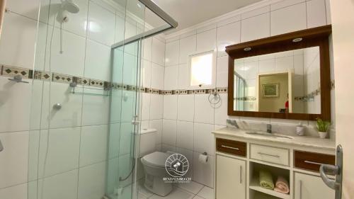 a bathroom with a shower and a toilet and a mirror at Casa centro de Torres – 500 mts do mar in Torres