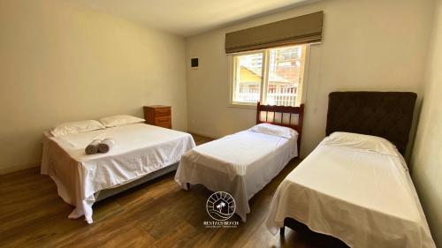a room with two beds and a window at Casa centro de Torres – 500 mts do mar in Torres