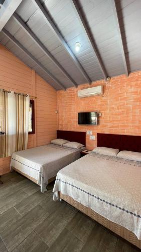 a room with two beds and a brick wall at Pousada Chalés Beach - Praia do Rosa in Praia do Rosa