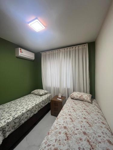 two beds in a room with green walls at Impera House Terreo Ar nos 2 quartos in Imperatriz