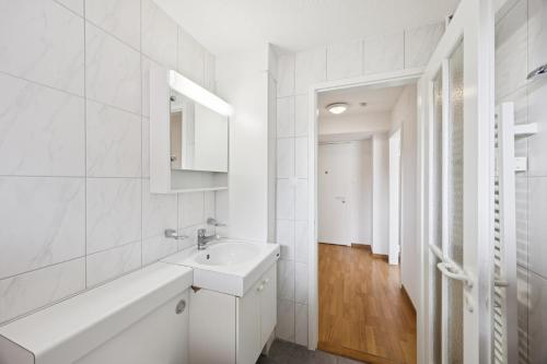 a white bathroom with a sink and a mirror at Very centrally located studio - Crown 15 in Zurich