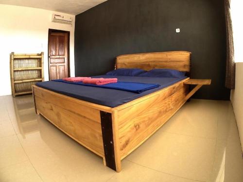 a large wooden bed with blue pillows in a room at East Lombok Dive Hotel - Rooms on the beach with seaview in Labuhanpandan