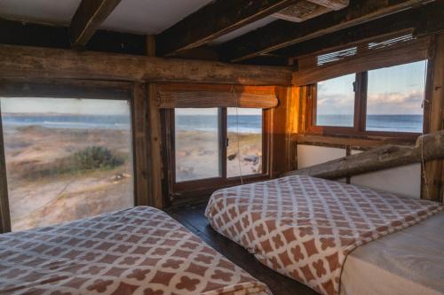 a bedroom with two beds in a room with windows at Narakan Cabo Polonio in Cabo Polonio