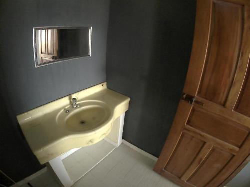 a bathroom with a sink and a wooden door at East Lombok Dive Hotel - Rooms on the beach with seaview in Labuhanpandan