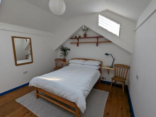 a bedroom with a white bed and a staircase at Jay's Cabin in Skibbereen
