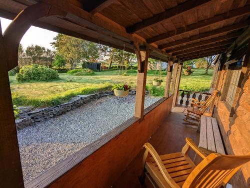 a porch with two wooden chairs and a bench at Jay's Cabin in Skibbereen