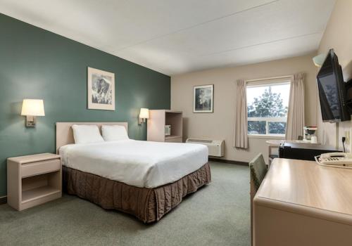 a hotel room with a large bed and a desk at Heritage Inn Hotel & Convention Centre - Taber in Taber