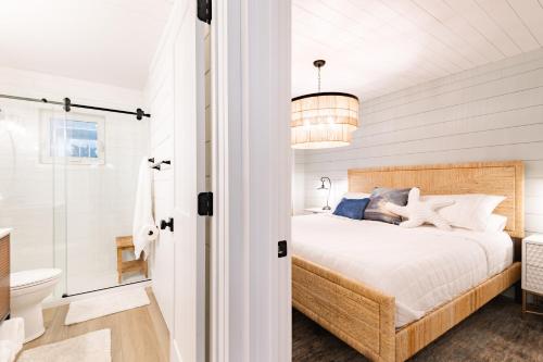 a white bedroom with a bed and a bathroom at Beachfront Corner Condo With Sunset Gulf Views in Bradenton Beach