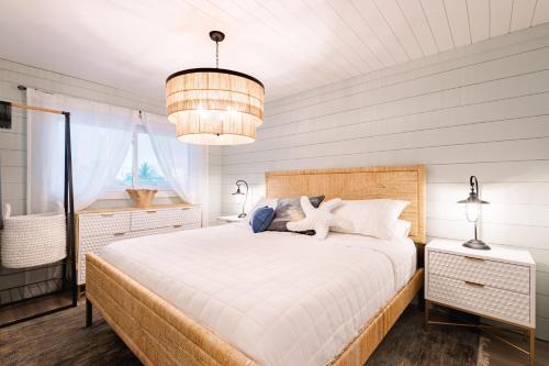a bedroom with a large white bed and a chandelier at Beachfront Corner Condo With Sunset Gulf Views in Bradenton Beach