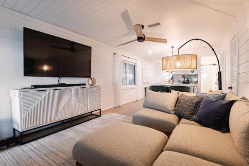 a living room with a couch and a flat screen tv at Beachfront Corner Condo With Sunset Gulf Views in Bradenton Beach
