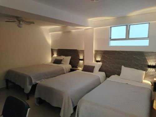 a room with three beds and a window at Hostal Mirador in Pisco