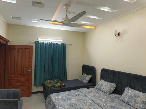 ein Wohnzimmer mit einem Bett und einem Deckenventilator in der Unterkunft IsLodge in Islamabad