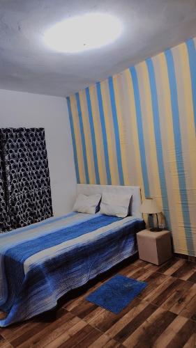 ein Schlafzimmer mit einem Bett mit blauen und gelben Streifen in der Unterkunft Refúgio Ibiúna in Ibiúna