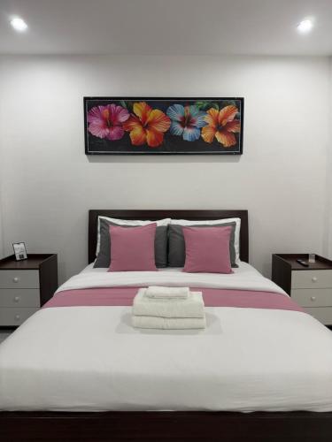 a bedroom with a large white bed with pink pillows at Viva La Rosa Hometel in Anda