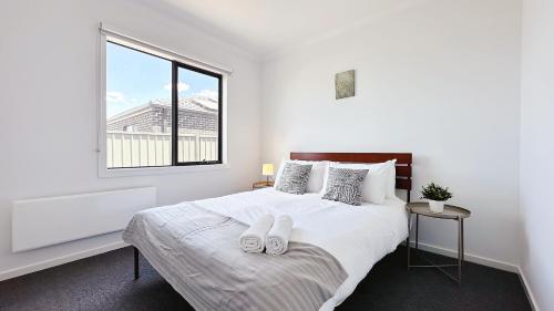 a white bedroom with a bed with two towels on it at Lyra 2026 Home by GoodLive in Beveridge