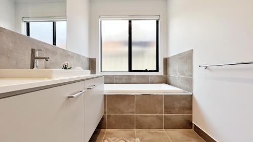 a bathroom with a tub and a sink and a window at Lyra 2026 Home by GoodLive in Beveridge