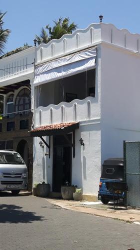 a white building with a car parked in front of it at Seagreen Guesthouse - Galle Fort in Galle