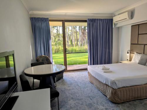a hotel room with a bed and a table and a window at Island Palms Motor Inn in Forster