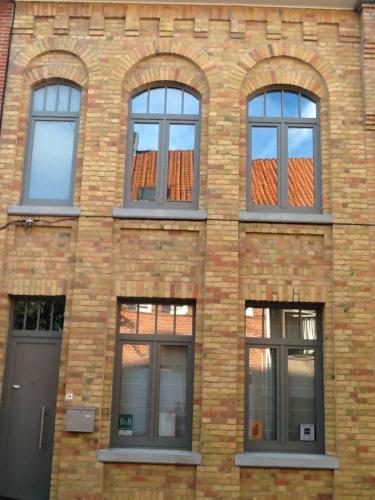a brick building with four windows and a door at Guesthouse Oude Houtmarkt in Ypres