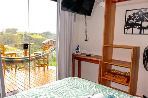 a bedroom with a bed and a balcony at chalé com Hidro e Vista panorâmica para Serra in Paraisópolis