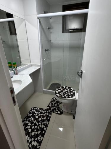 a bathroom with a shower and a toilet with a black and white floor at Loft reserva do Sahy- condado in Mangaratiba