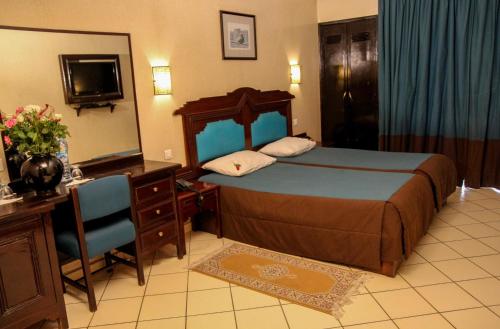 a bedroom with a bed and a desk and a mirror at New Farah Hotel in Agadir