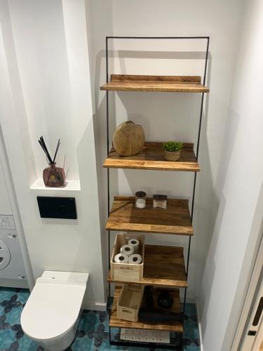 a bathroom with a toilet and wooden shelves at Apartamento acogedor frente a Plaza del Cedro in Valencia
