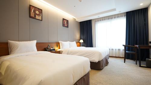 a hotel room with two beds and a window at Gloucester Hotel Jeonju in Jeonju