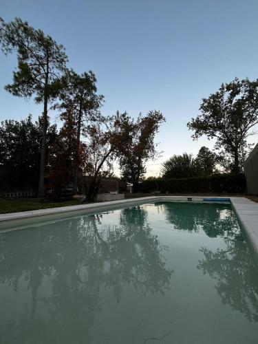 an empty swimming pool with trees in the background at Casa con pileta Funes in Funes