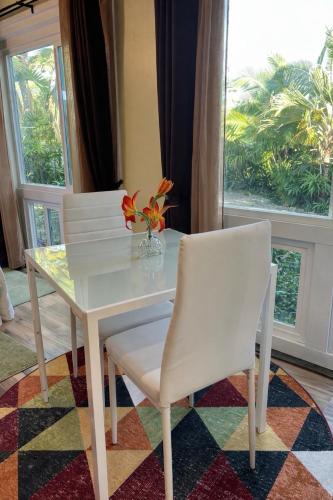 a white dining room table with two chairs and a vase with flowers at Kona Nook - Cozy Studio with Island Warmth in Kailua-Kona
