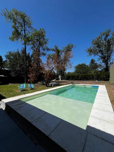 a swimming pool with two blue chairs in a yard at Casa con pileta Funes in Funes