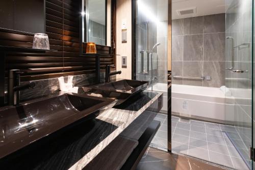 a bathroom with two sinks and a bath tub at First Hotel Kanazawa in Kanazawa