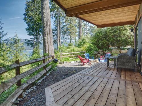 a wooden deck with a table and chairs on a house at Oceanfront view 2 entertainment areas -Pet Friendly in Port Renfrew