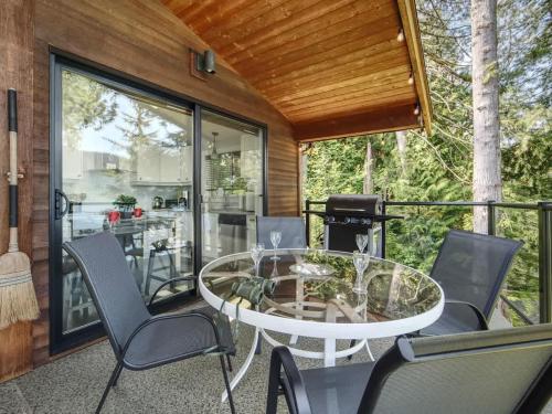 a screened in porch with a glass table and chairs at Oceanfront view 2 entertainment areas -Pet Friendly in Port Renfrew