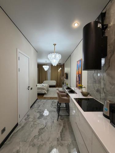 a kitchen with a counter and a living room at The Grand CentraL Studio & Люкс Студия в Центре Города Алматы in Almaty