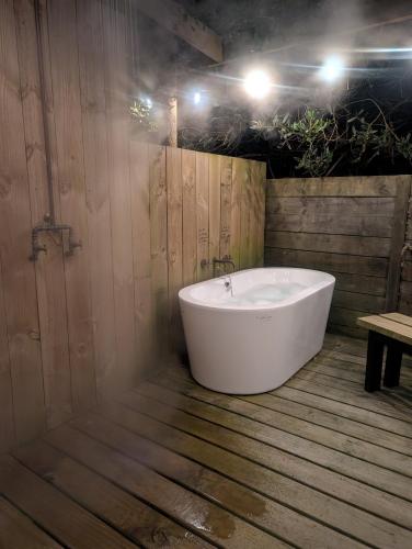 a bath tub in a bathroom with a wooden floor at Salty Devil's Rest - Coastal Wilderness Shack in Arthur River
