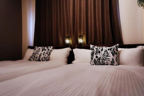 two beds in a hotel room with white sheets and pillows at Clair US Tokyo-Disney & Tokyo Sightseeing Base in Tokyo