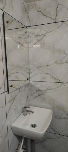 a white sink in a bathroom with marble walls at Ivory Suites Meadows in Kozhikode