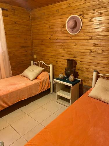 two beds in a room with wooden walls at Cabañas Los Lapachos in Chicoana
