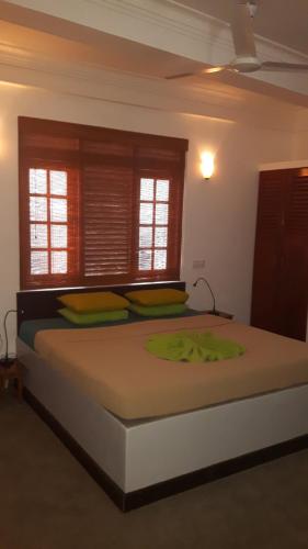 a large bed in a room with two windows at Seagreen Guesthouse - Galle Fort in Galle